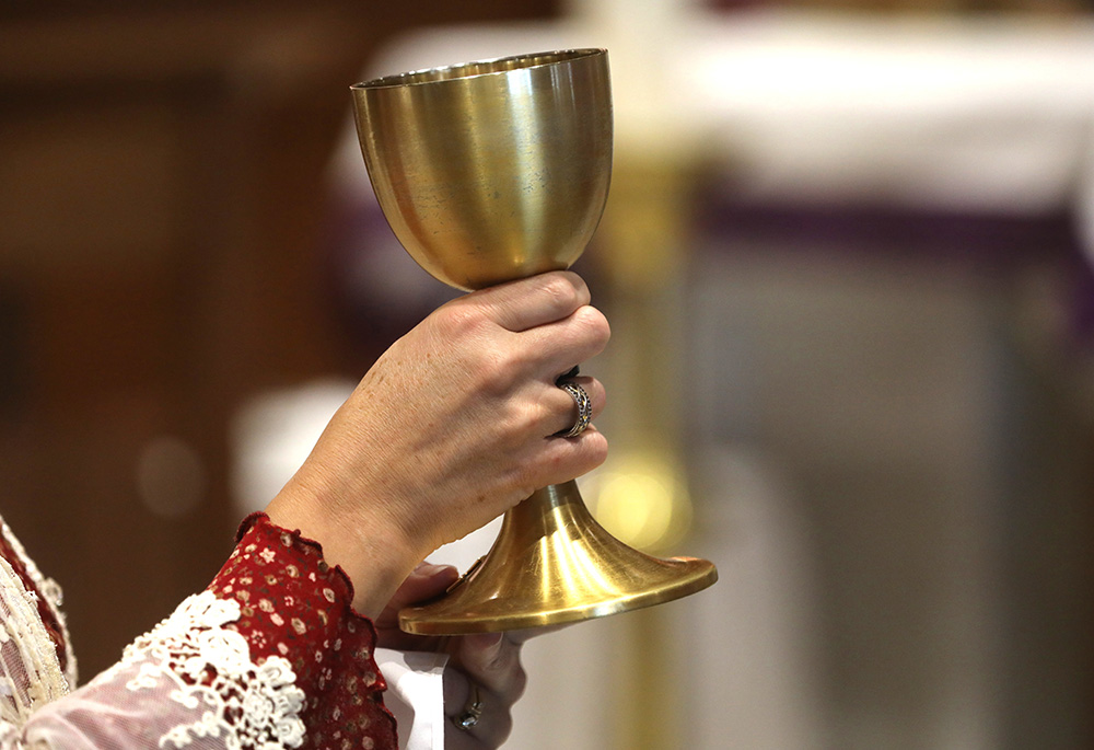 An extraordinary minister of holy Communion holds the chalice during Communion at Sacred Heart Church, Dec. 10, 2023, in Prescott, Arizona. (OSV News/Bob Roller)