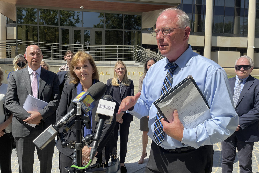 Lorenz stands outside courthouse, talking at podium with microphones.