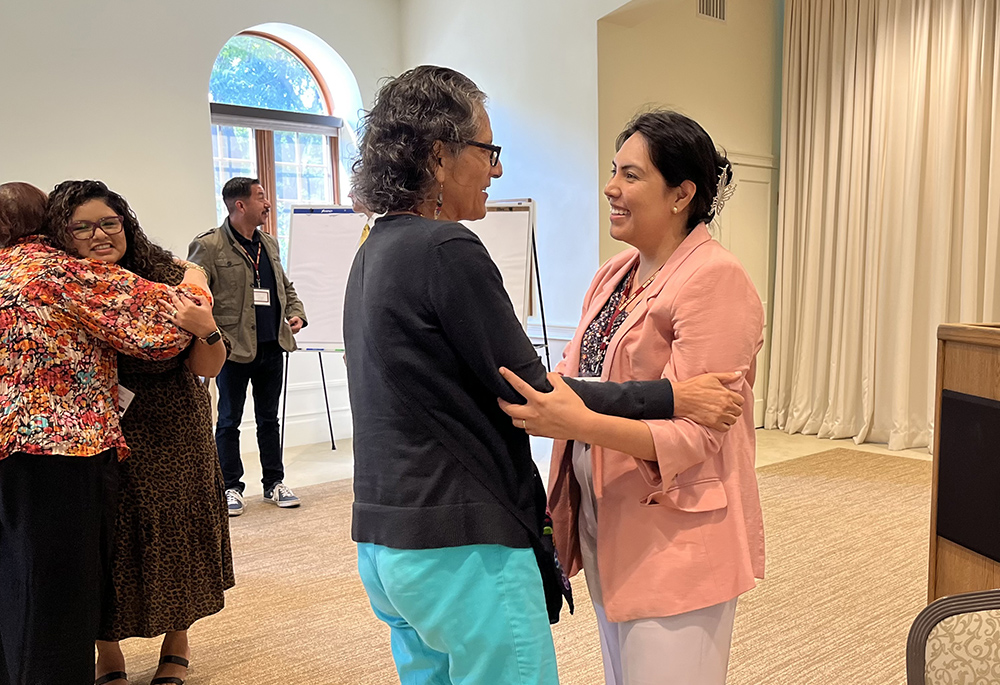 Brenda Noriega-Flores, Boston College doctoral candidate and a project coordinator in Nuevo Momento, at right, gives a gesture of peace to Elena Segura from Pastoral Migratoria at the end of one of the talks. (Luis Donaldo González)