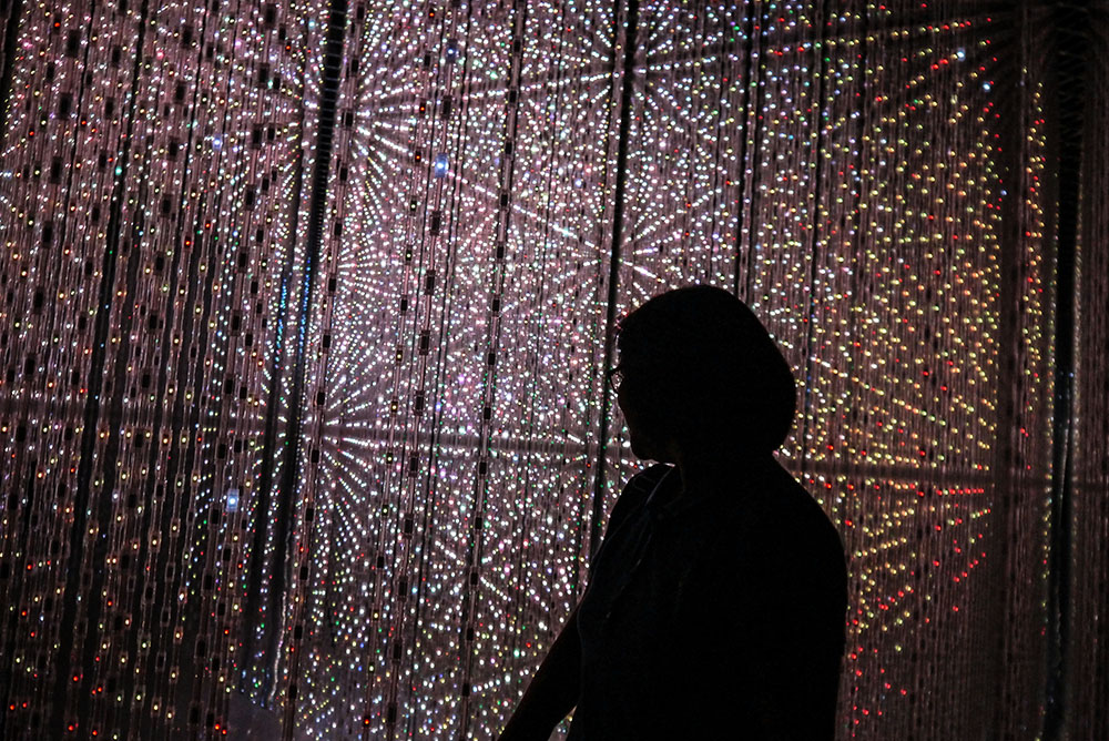 Woman standing in front of a grid of electric lights (Unsplash/Hannah Sibayan)