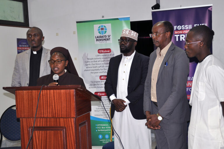 The presenters stand behind Sister Wangare who speaks at podium.