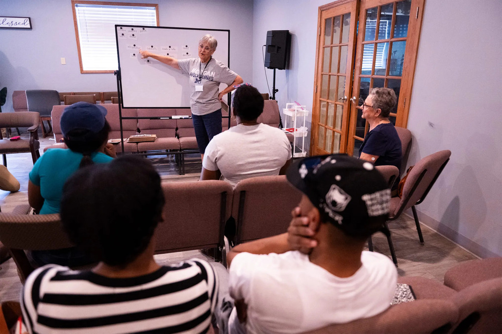 Kaufman stands in front of whiteboard, people sit in chairs listening.