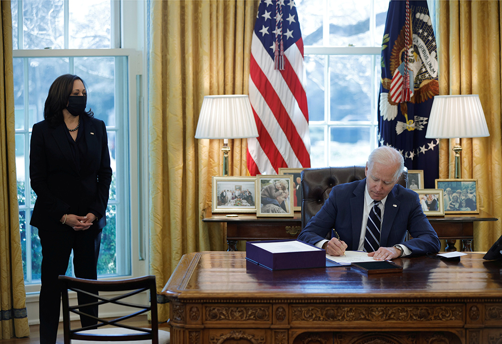 President Joe Biden signs the American Rescue Plan into law at the White House in Washington March 11, 2021. Also pictured is Vice President Kamala Harris. (CNS/Reuters/Tom Brenner)