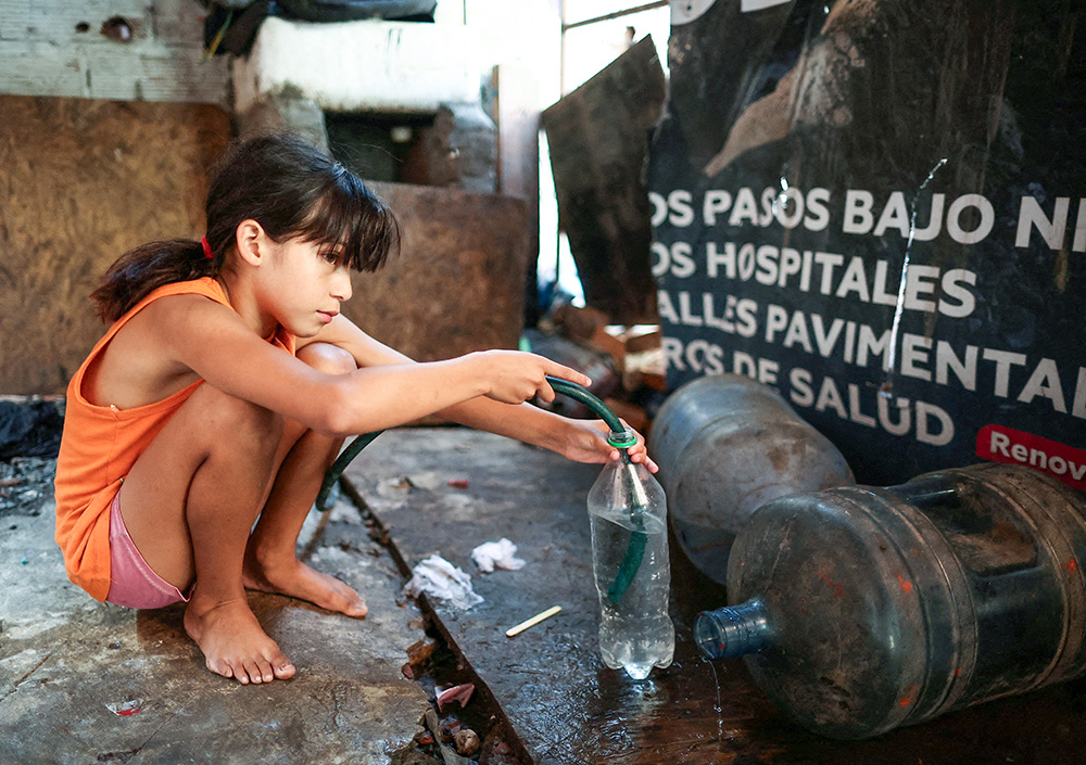 A girl fills a bottle with a hose to bring drinking water to her home in a poor section of Buenos Aires, Argentina, Feb. 27, 2024. (OSV News/Reuters/Agustin Marcarian)