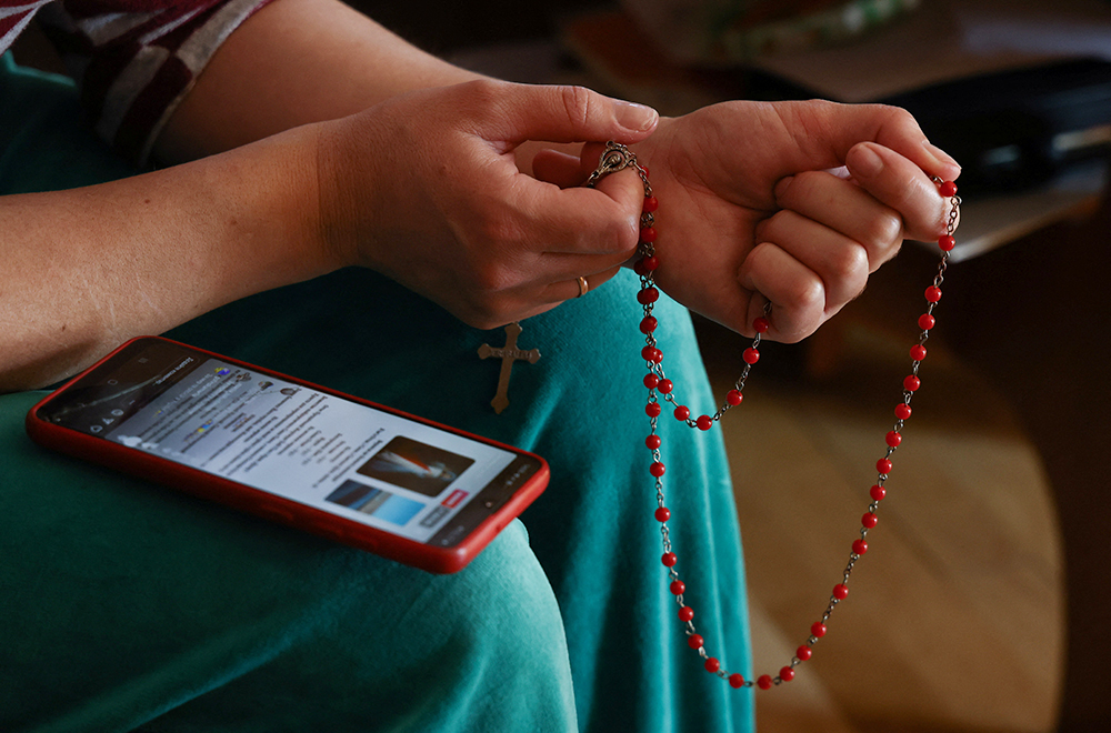 A Ukrainian woman who fled Russia's invasion of Ukraine prays with a rosary and prayers on her mobile phone in Lubaczow, Poland, March 21, 2022. (OSV News/Reuters/Kacper Pempel)