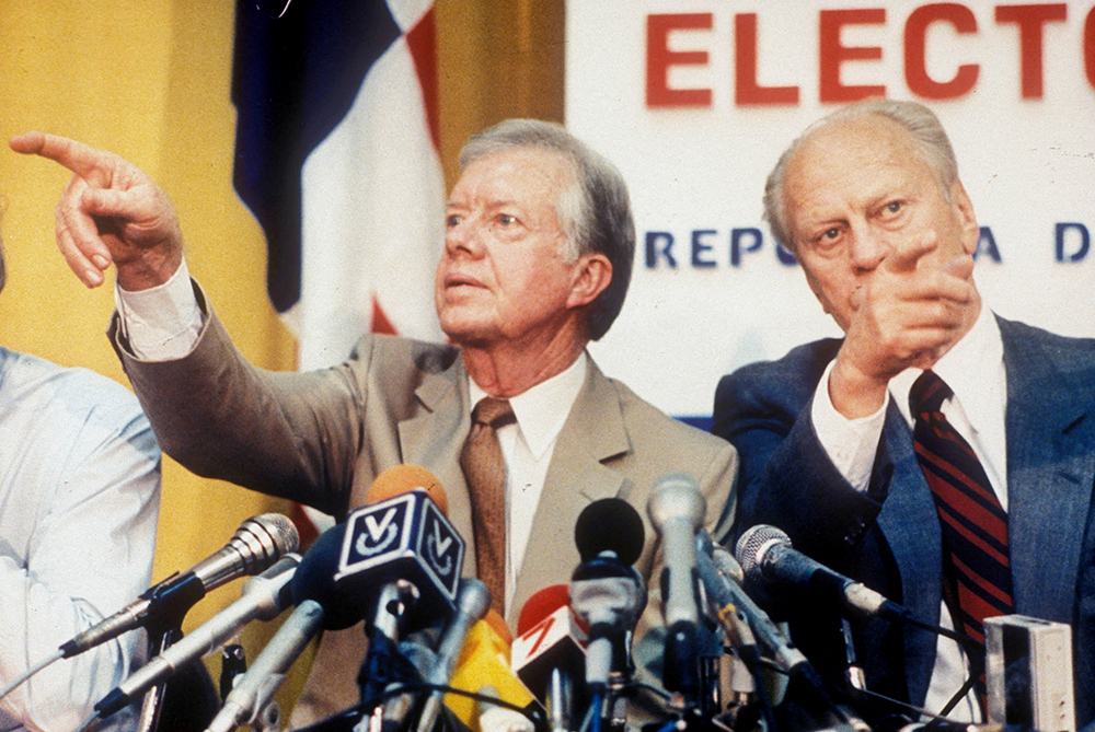 Former U.S. Presidents Jimmy Carter and Gerald Ford point in different directions while calling on reporters wanting to ask questions at a press conference in Panama City, Panama, May 5, 1989. (Reuters/Dematteis/File photo)