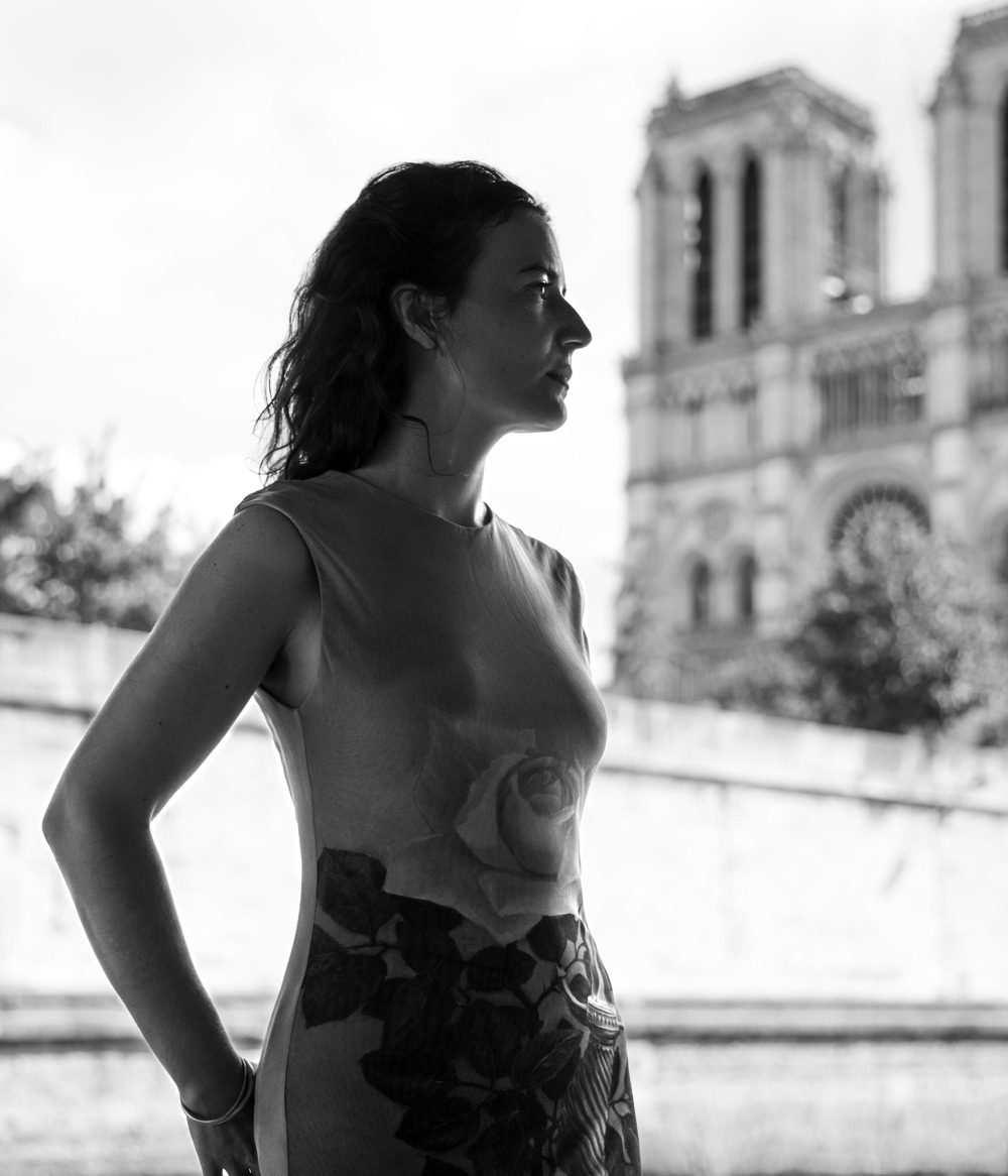 Black and white portrait of Borel standing in front of Notre Dame de Pari. 