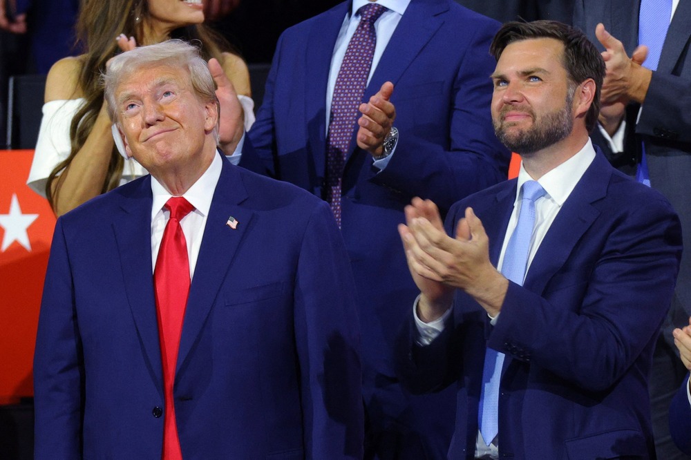 Trump and Vance stand looking up and smiling.