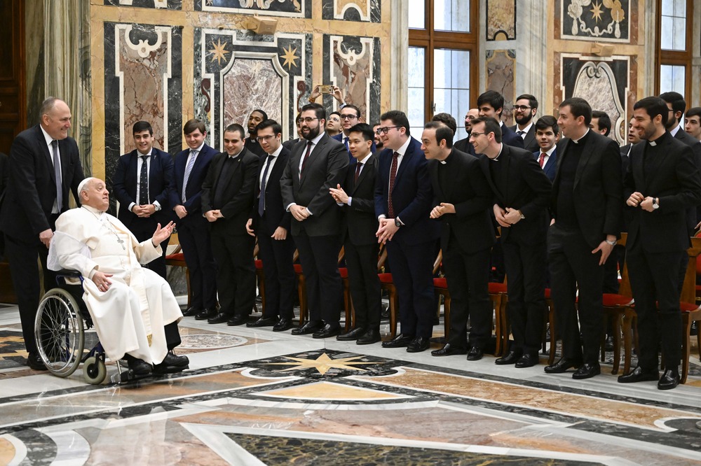 Seminarians in black lined up as Francis enters in wheelchair.