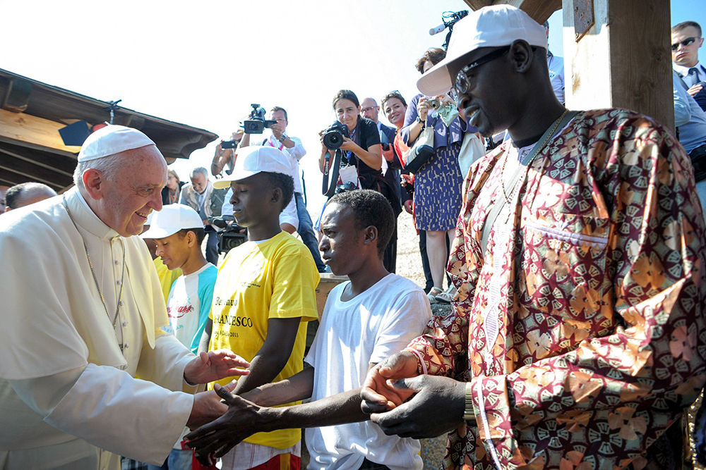 Pope Francis greets immigrants at the port in Lampedusa, Italy, in this file photo July 8, 2013. During his visit, the pontiff urged people not to be part of the "globalization of indifference" to the plight of the millions worldwide who are immigrants and refugees. (CNS/L'Osservatore Romano via CPP)