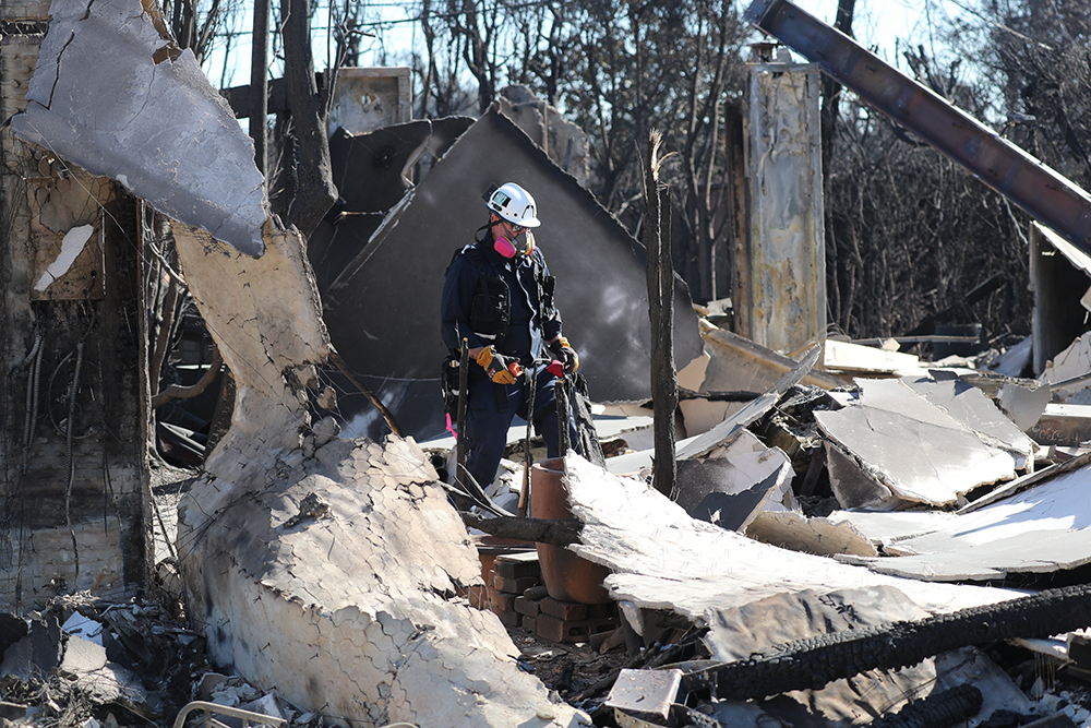 A member of California Regional Urban Search and Rescue Task Force 5 (CA-RTF-5) looks over a destroyed home in Pacific Palisades on the west side of Los Angeles Jan. 15, 2025, in the aftermath of the wildfires. (OSV News/Bob Roller)