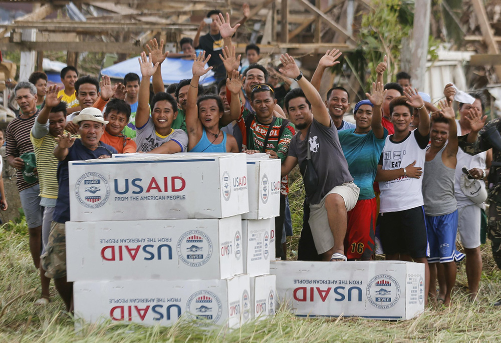 Filipinos are seen in a 2013 photo showing gratitude and waving to the crew of a U.S. Navy aircraft after receiving aid from U.S. Agency for International Development in the remote village of Guiuan, Philippines, following one of the most powerful typhoons ever recorded. (OSV News/Reuters/Wolfgang Rattay)