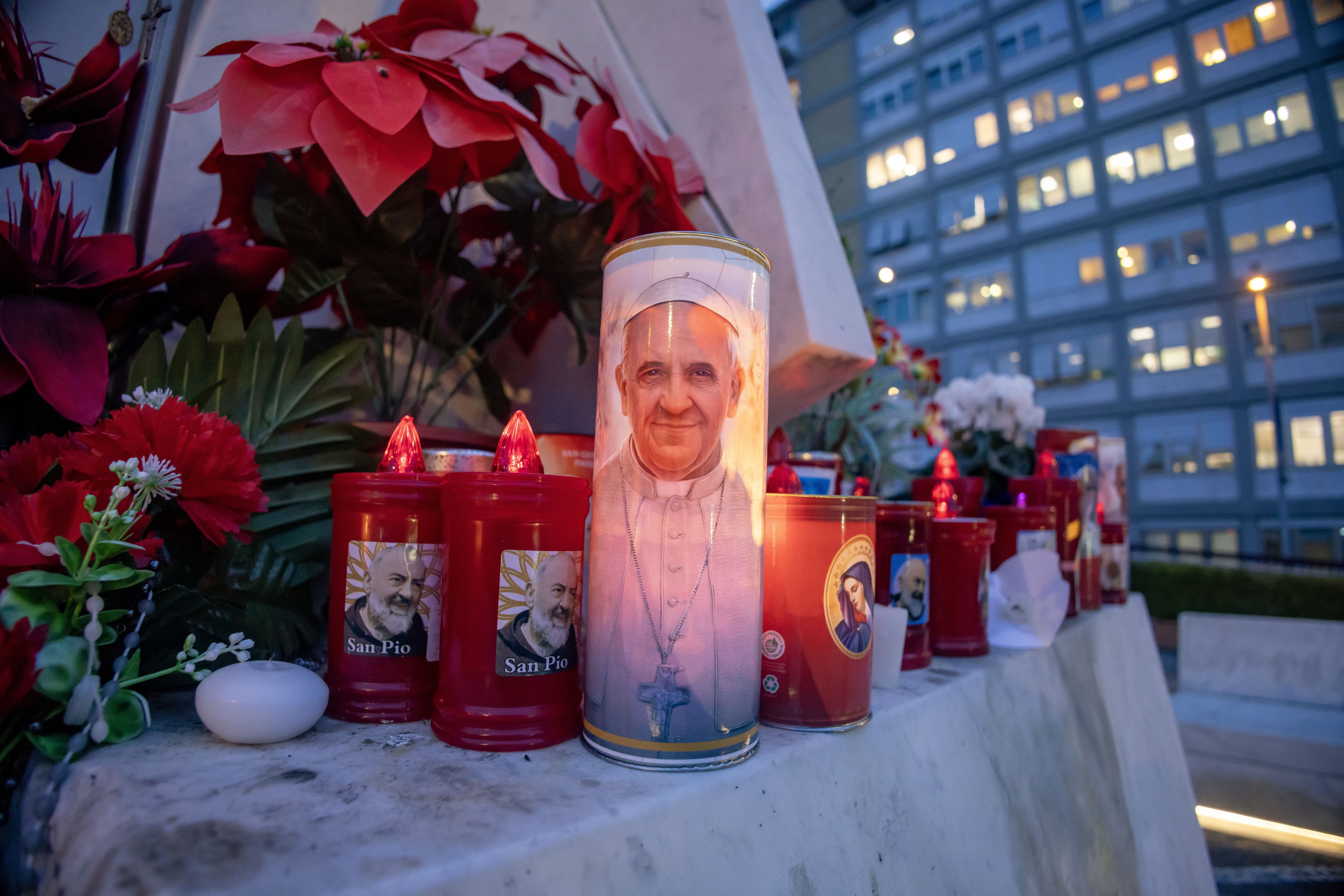  Votive candles and flowers are seen at the base of a statue of St. John Paul II outside Rome's Gemelli hospital Feb. 19, 2025, where Pope Francis is being treated for double pneumonia. (CNS photo/Pablo Esparza)