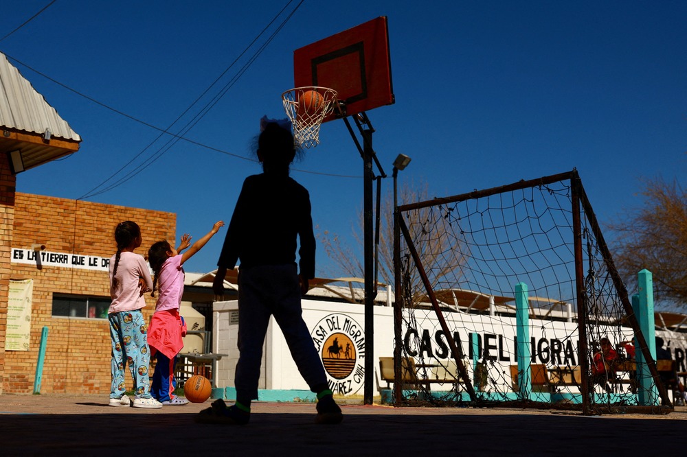 Three young girls play basketball outdoors. 