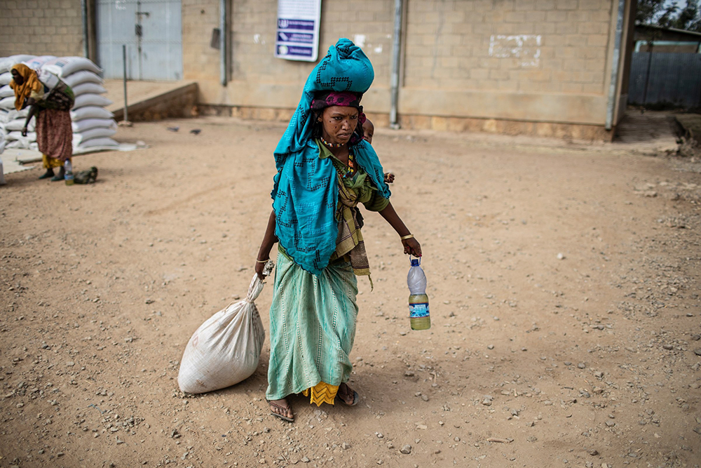 A woman carries home her rations of wheat, yellow split peas and cooking oil following a distribution of U.S. Agency for International Development (USAID) food in a rural area of Ethiopia's Oromia region Feb. 9, 2019. (OSV News/Courtesy of CRS/Will Baxter)