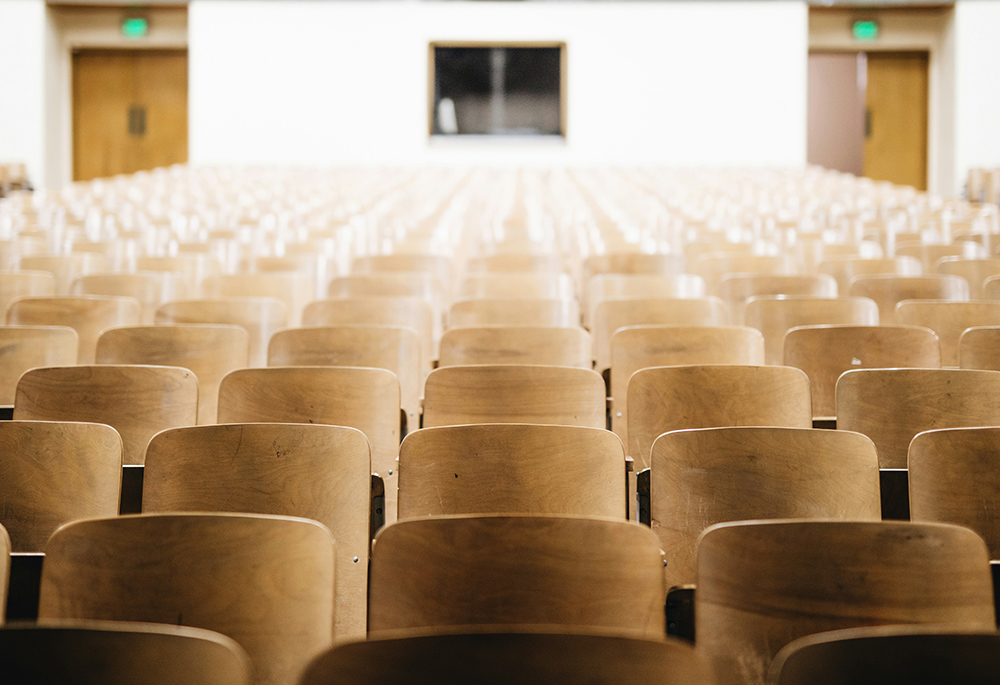 A photo illustration shows rows of seats in an auditorium or a lecture hall setting. (Unsplash/Nathan Dumlao)