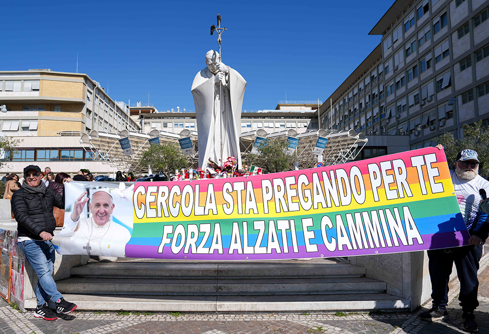 People hold a banner with a greeting in Italian for Pope Francis outside Rome's Gemelli Hospital on March 6. The banner says, "Cercola is praying for you. Stay strong, rise and walk." The phrase "rise and walk" is from the Acts of the Apostles, and Cercola is a town near Naples. (CNS/Lola Gomez)