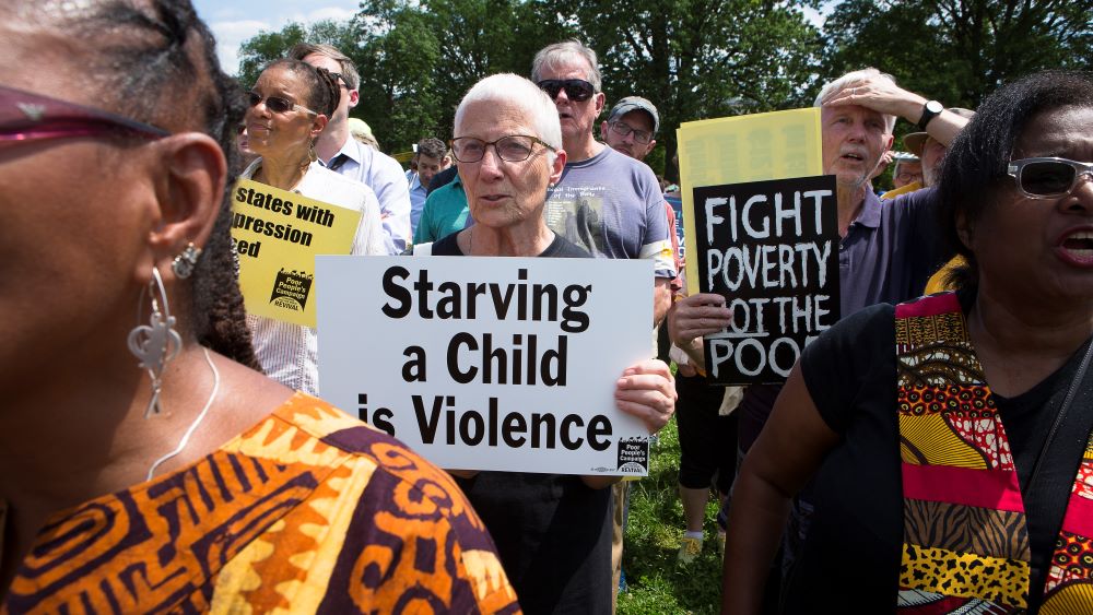 Marie Dennis holds sign at protest.