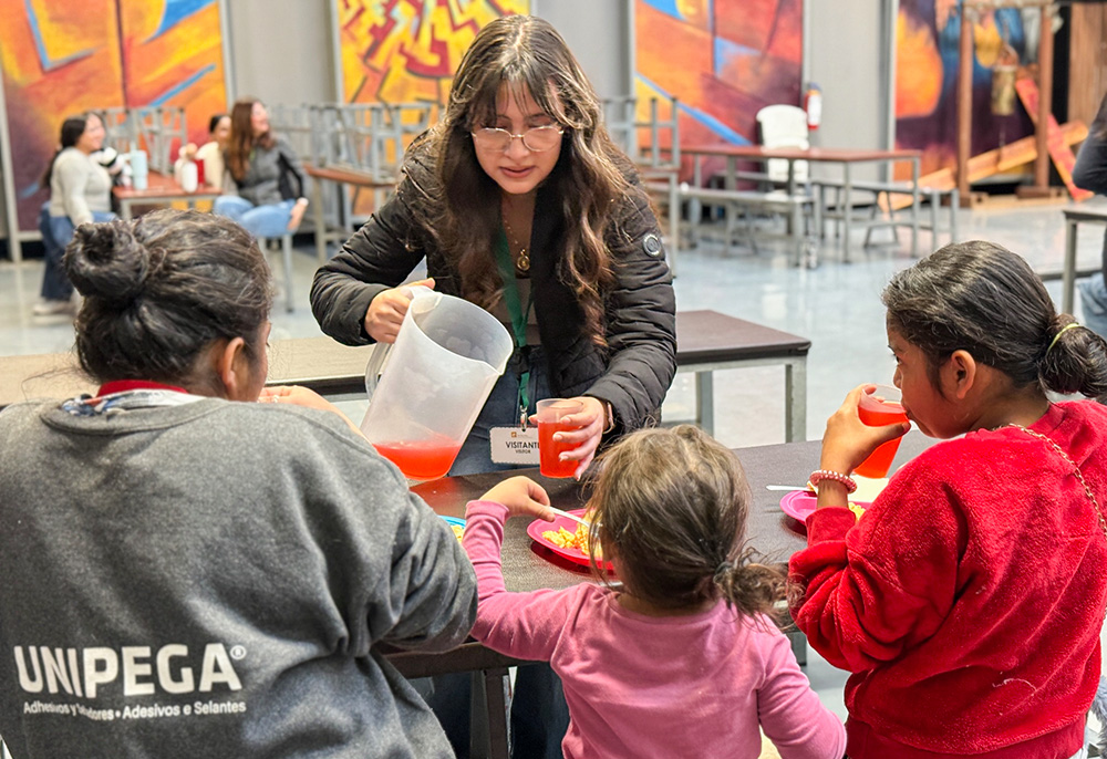 Sophomore Victoria Mendoza-Cardena, 16, from Sacred Heart Preparatory in Atherton, California, serves a Central American mother and her two young daughters breakfast on Feb. 19, 2025, at the Kino Border Initiative in Nogales, Mexico. (Anita Snow)