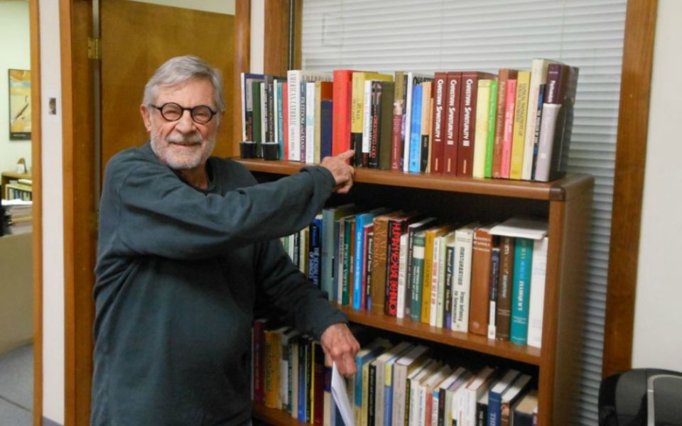 Richard Sipe, in the offices of BishopAccountability.org, points to a collection of his books that he gave to the church watchdog organization. (Courtesy of Fr. Tom Doyle)