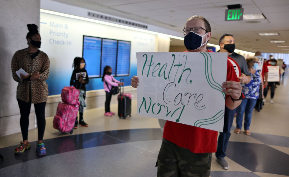 A person holds a sign as laid off LAX Airport workers protest for an extension of health care benefits by concessions companies in Los Angeles Sept. 24. (CNS/Reuters/Lucy Nicholson)