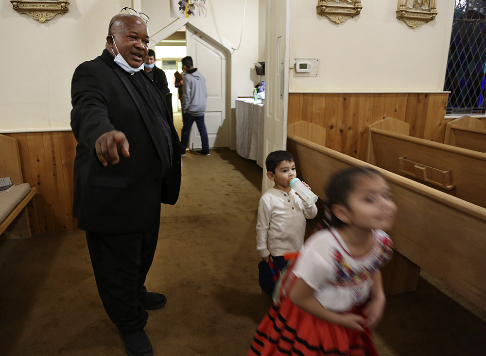 Fr. Athanasius Abanulo, left, talks to siblings Germany and Samantha Gonzalez at Holy Family Catholic Church in Lanett, Alabama, on Dec. 11, 2021. (AP/Jessie Wardarski)