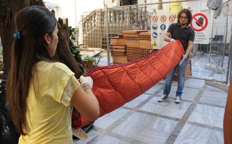 Volunteers fold blankets at a reception center for migrants in a church in Palermo, Sicily, in Italy. (Photos by Megan Sweas)