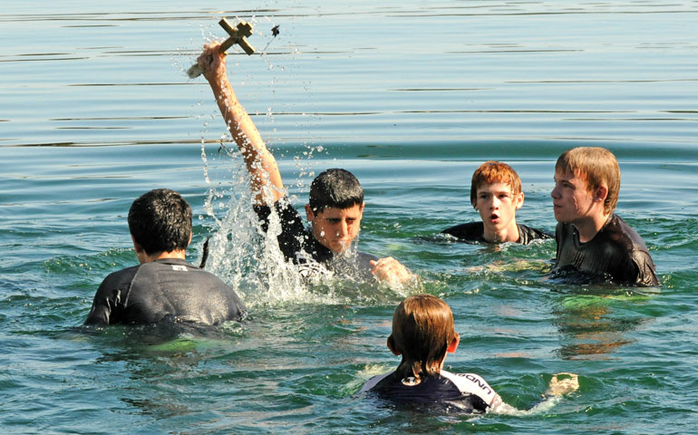 George Avdella holds a cross above his head after retrieving it from Lake Eola during the Epiphany celebration of St. George Orthodox Church in Orlando, Fla., on Jan. 8, 2012. (Newscom/Polaris/Paul Hennessy)