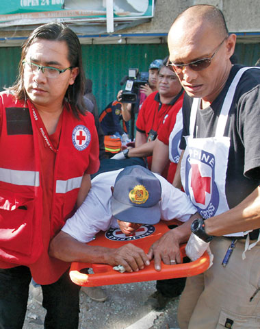 Philippine Red Cross personnel carry a wounded hostage rescued from Moro Islamic Liberation Front rebels  in Zamboanga Sept. 13. (CNS/Reuters/Erik De Castro)