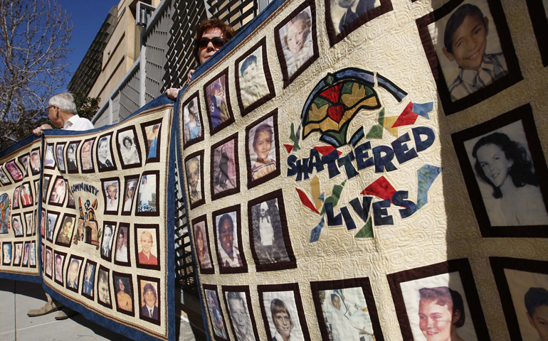 People stand outside the Cathedral of Our Lady of the Angels Feb. 1, 2011, holding quilts bearing photos of victims of sexual abuse by priests of the Los Angeles archdiocese. (CNS/David McNew, Reuters)