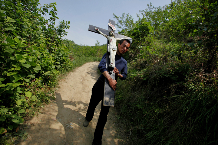 In this 2013 file photo, a Chinese Catholic carries a crucifix during a pilgrimage in the Shaanxi province of China. Hong Kong Cardinal John Tong Hon has asked Communist Party chiefs in Beijing to order a halt to an ongoing cross-removal campaign from churches in Zhejiang province. (CNS photo/Wu Hong, EPA)