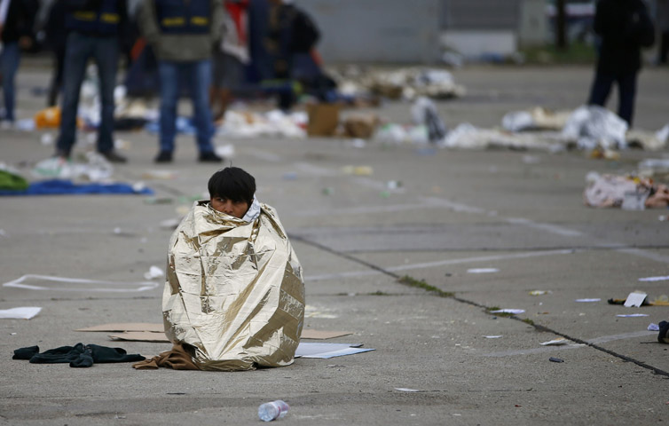 A migrant sits wrapped in an emergency blanket at the crossing point between Hungary and Austria in Nickelsdorf, Austria, Sept. 11. (CNS/Leonhard Foeger, Reuters)