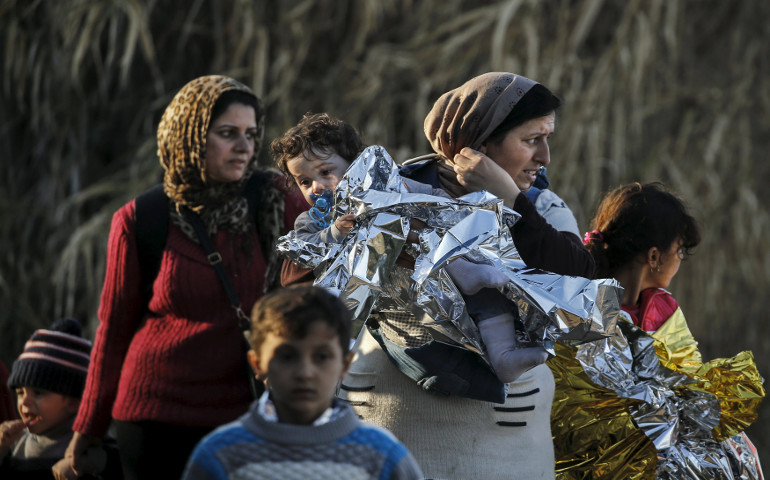 A Syrian refugee carries her child in a thermal blanket as refugees and migrants arrive Nov. 10 on an overcrowded boat on the Greek island of Lesbos. (CNS/Reuters/Alkis Konstantinidis)