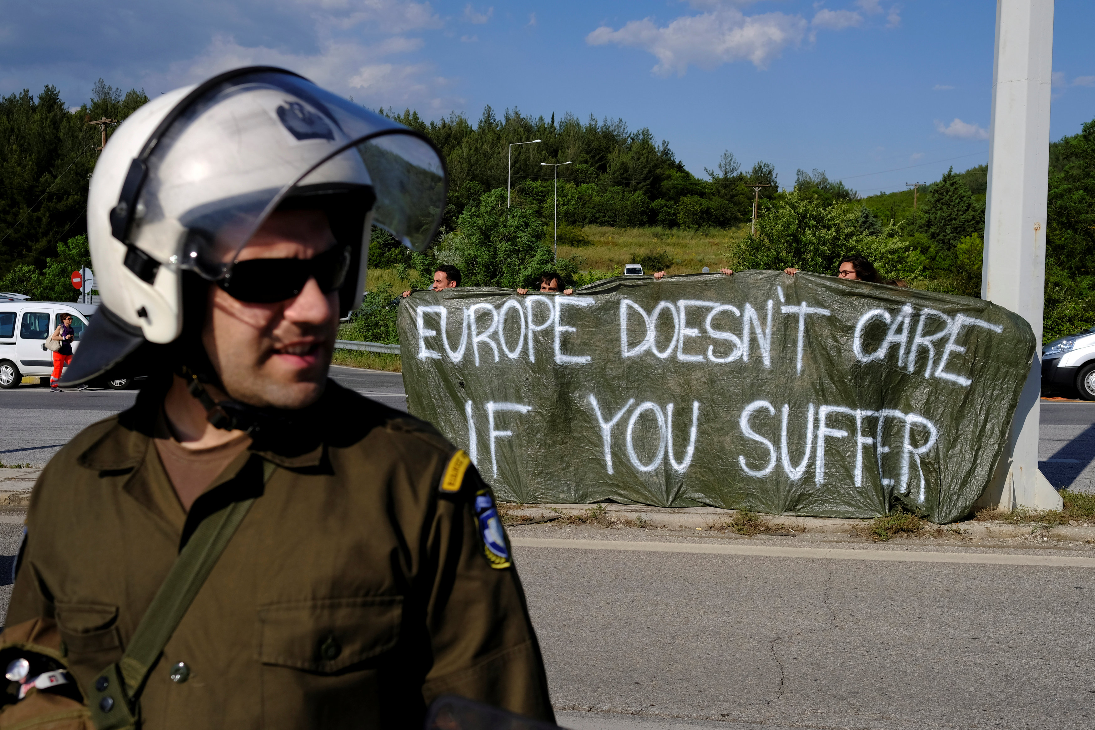 Protestors hold a banner on a highway during a police operation to evacuate a makeshift camp at the Greek-Macedonian border near the village of Idomeni, Greece, May 24. (REUTERS/Marko Djurica)