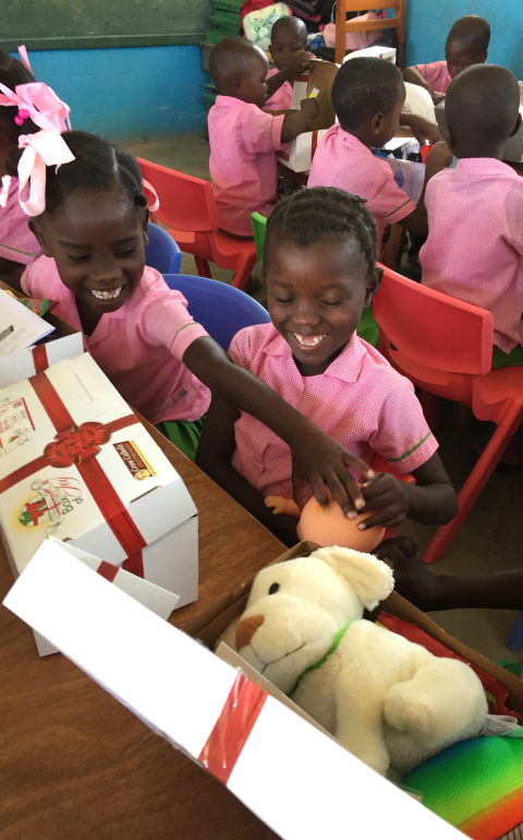 Children in Les Cayes, Haiti, open presents March 22 that they received through the Box of Joy program of Cross Catholic Outreach, a Florida based relief and development agency. (CNS photo/courtesy of Cross Catholic Outreach)