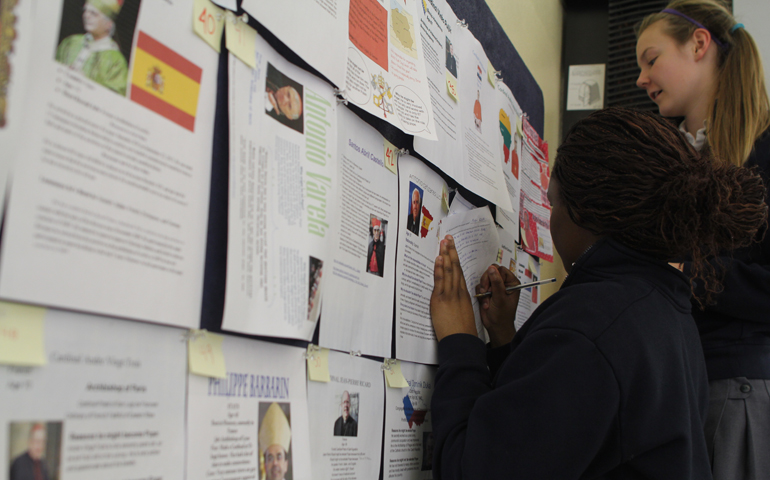 Freshmen Chioma Okuagu, left, and Madison Heide work on narrowing down their brackets for who they think should be Pope. (NCR photo: Eloísa Pérez-Lozano)