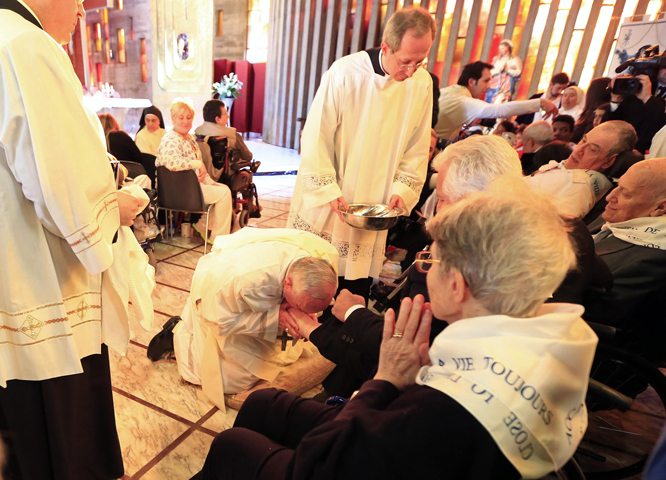 Pope Francis kisses the foot of a disabled person at Our Lady of Providence Center on Thursday during Holy Thursday Mass in Rome. (CNS/Reuters/Tony Gentile)