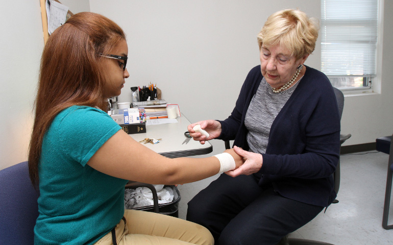 School nurse Mary Ashcroft wraps 10th-grader Krystal Panigua's sprained wrist with gauze at Cristo Rey New York High School in the East Harlem neighborhood of New York May 27. (CNS/Gregory A. Shemitz)