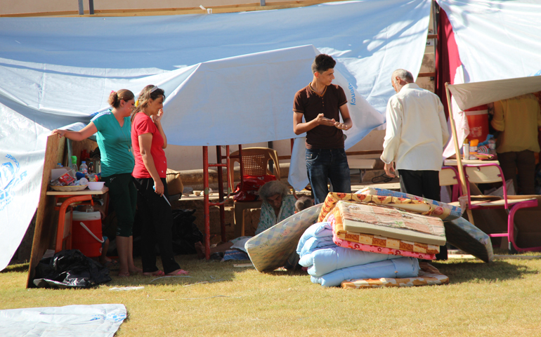 People displaced by violence stand outside their tent at St. Joseph Chaldean Catholic Church in Ankawa, Iraq, Aug. 14. (CNS/Courtesy Aid to the Church in Need-USA) 