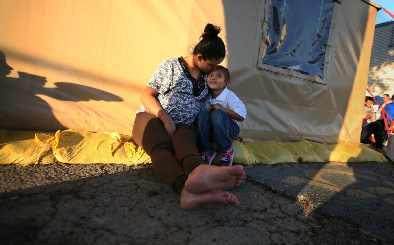 Yesenia Matilde Martinez of Guatemala kisses her daughter, Leslie Jasmin Martinez, 5, as they wait for a bus ride at the Humanitarian Respite Center on the U.S.-Mexico border in McAllen, Texas. They are among the thousands of families that have stayed at the center after crossing the border. Overseen by Catholic Charities of the Brownsville Diocese, a special facility will be built to house the center's work. (Nuri Vallbona)