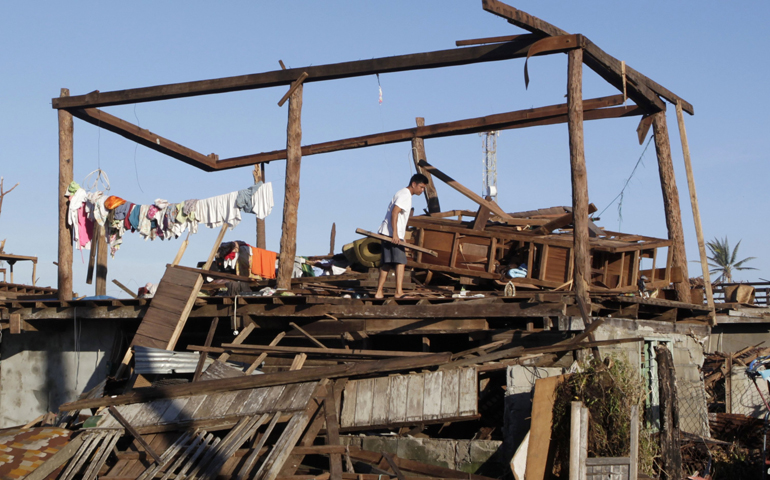 A man stands inside a frame of his house Tuesday after it was destroyed a week earlier by 120-mph winds in the coastal town of Cateel, Philippines. Struggling to find adequate shelter to escape the heat of the midday sun, survivors of Typhoon Bopha scavenged whatever debris they could to build makeshift housing across storm-ravaged provinces of the Philippines. (CNS/Reuters/Erik De Castro)