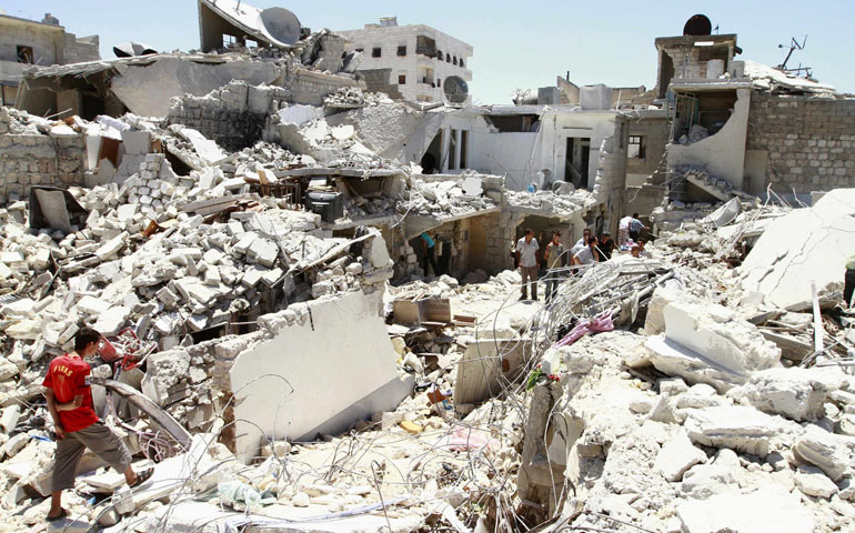 Residents rummage through the damage and debris left of their homes for their belongings July 27 after what activists said was an air attack from forces loyal to Syria's President Bashar Assad in Aleppo. The war in Syria is like a factory churning out nothing but death, destruction and suffering, said Archbishop Mario Zenari, the Vatican nuncio to Syria. (CNS/Reuters/Hamid Khatib)