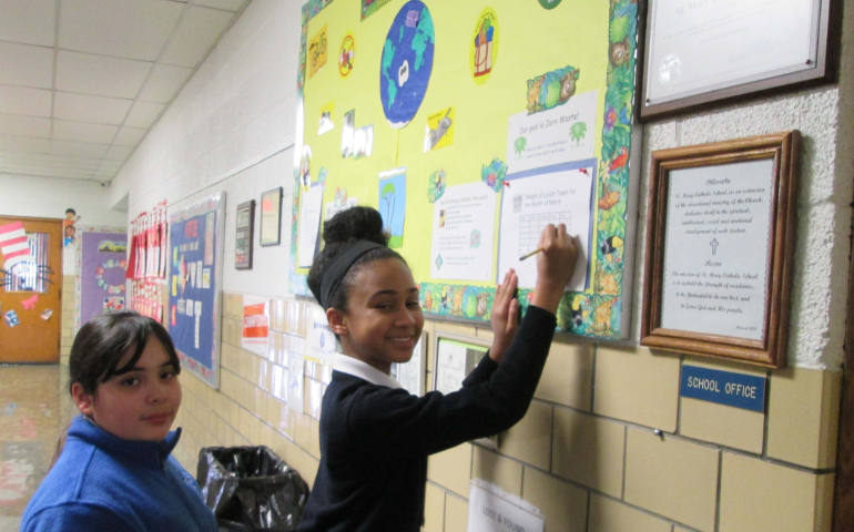 Students at St. Mary Catholic School, in Wayne, Mich., record the trash weight for waste-free lunch day. The bulletin is outside the school’s main office where students can track progress. (Pat Wallace)