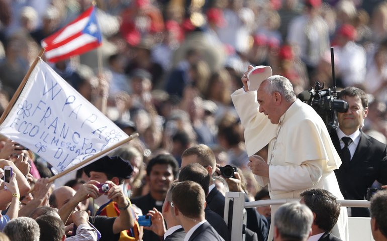 Pope Francis tries on a zucchetto given by Providence College student Joseph Day at the general audience Wednesday in St. Peter's Square at the Vatican. The pope tried on the zucchetto, which had a hot pink sticky note stuck inside, then gave it back to Day. (CNS/Paul Haring) 