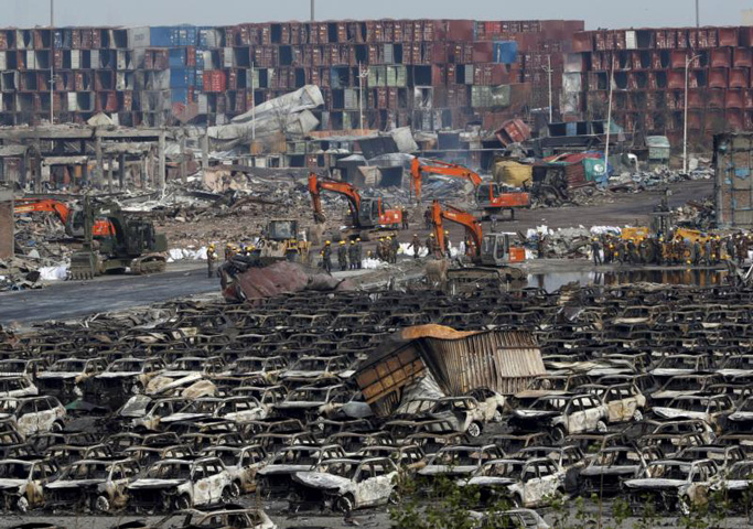 Rescuers stand near damaged vehicles Aug. 17, close to the site of Aug. 12 explosions in Tianjin, China. (CNS/Kim Kyung-Hoon, Reuters)