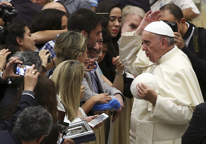 Pope Francis changes his cap during his general audience at the Vatican on Aug. 19, 2015. (Reuters/Alessandro Bianchi)