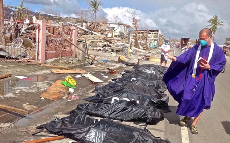 Order of Augustinian Recollects Fr. Charlie Orobia blesses bodies waiting to be buried after a storm surge from Super Typhoon Haiyan killed scores of people in Tacloban City. (Order of Augustinian Recollects Br. Jaazeal Jakosalem)