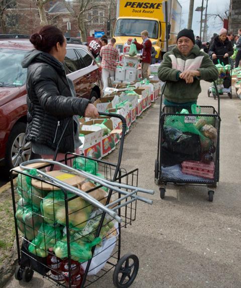 Neighbors prepare to take carts full of food home at the SSJ Neighborhood Center's monthly food distribution day, March 20 in Camden, New Jersey. (GSR photo/Dan Stockman)