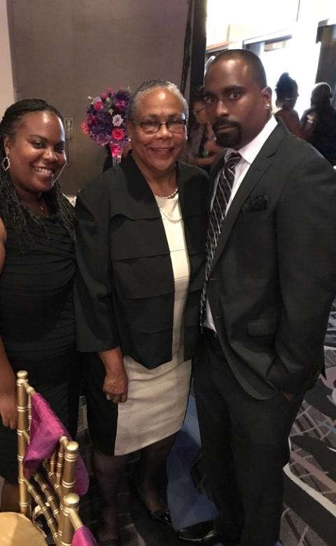 The three stand facing camera wearing black and white dress clothes.