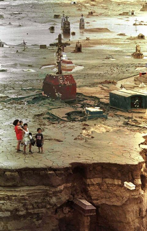 A family looks over a cemetery damaged by mudslides and flooding from El Niño rains in Trujillo, Peru, Feb. 12, 1998. (CNS/Reuters)